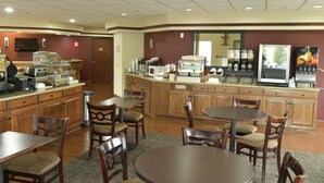Een restaurantgedeelte in een hotel, met houten meubels, een buffet en een koffiehoek.