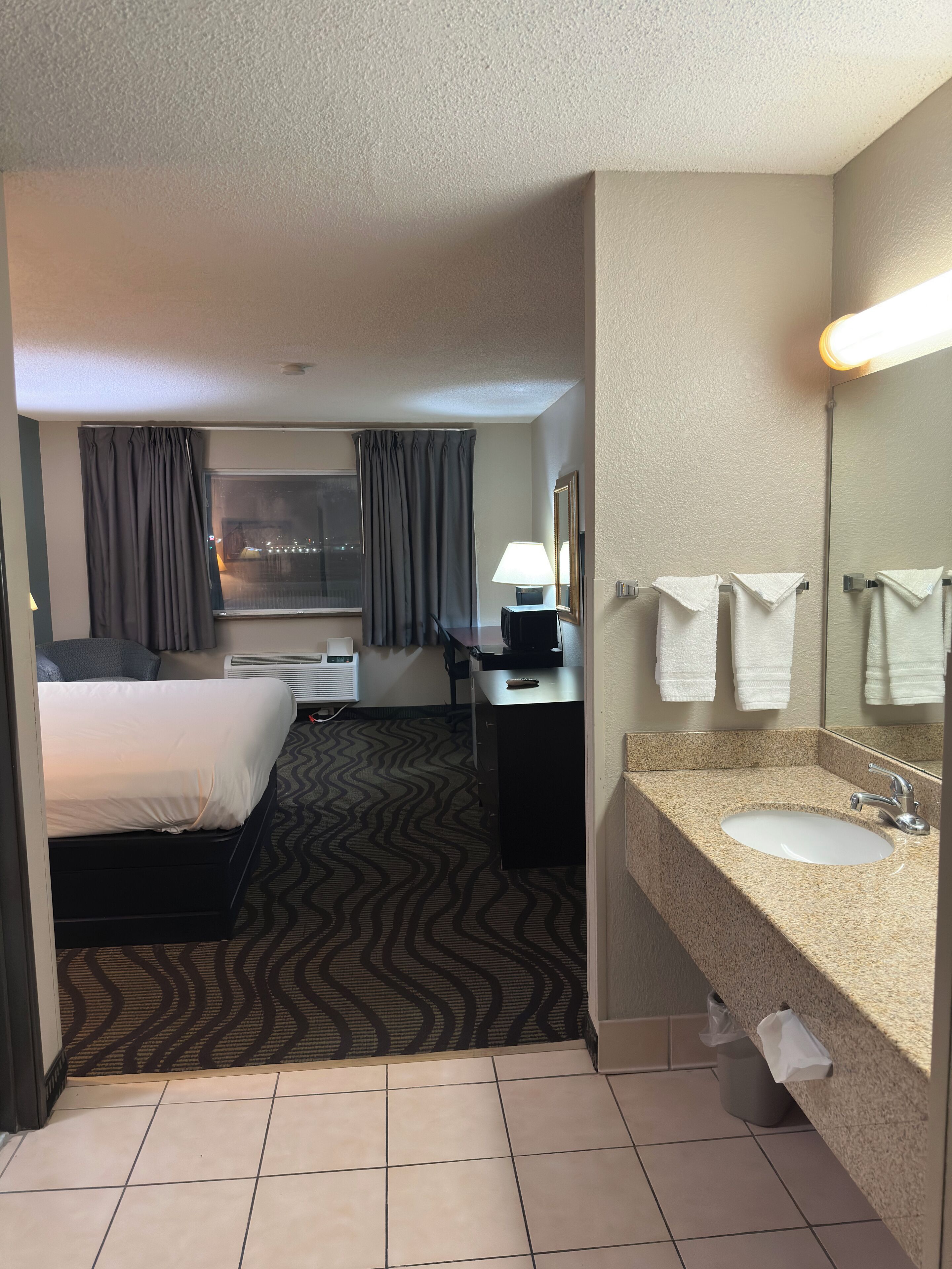 A hotel room with a bed, desk, and bathroom.