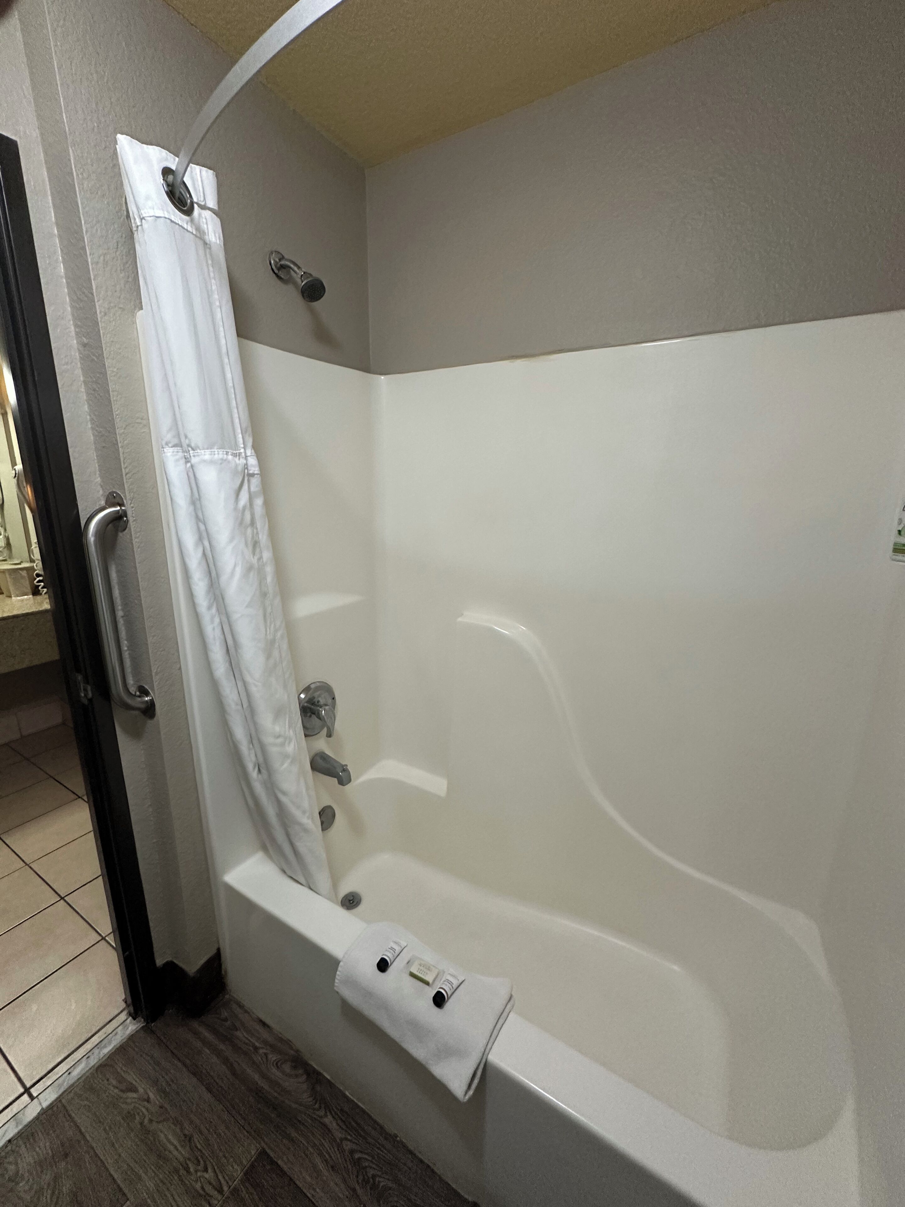 A bathroom with a bathtub, a shower curtain, and a towel rack.
