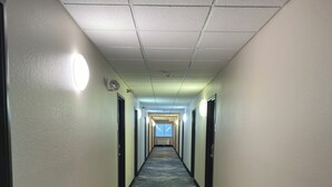 Een hotelgang met tapijtvloeren, witte muren en deuren aan beide zijden.