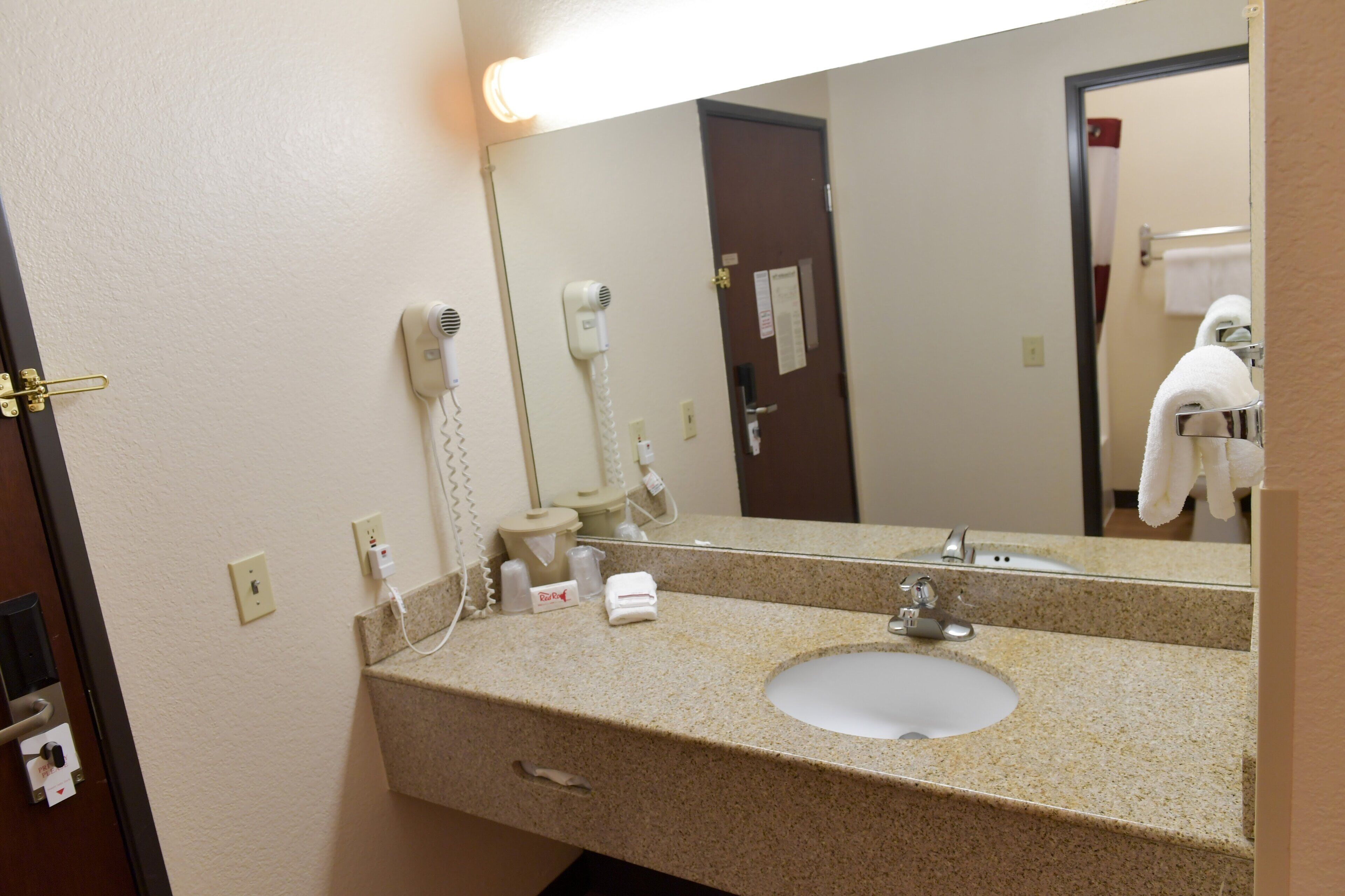 A hotel bathroom with a sink, mirror, hairdryer, and towel rack.