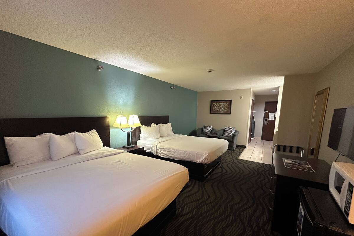 Une chambre d’hôtel avec deux lits, un bureau doté d’un micro-ondes et donnant sur le couloir.