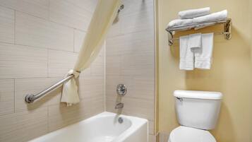 A bathroom with a bathtub, a shower curtain, a toilet, and a towel rack with towels.