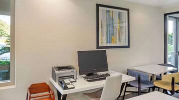 A modern office space with a desktop computer, printer, and two chairs.