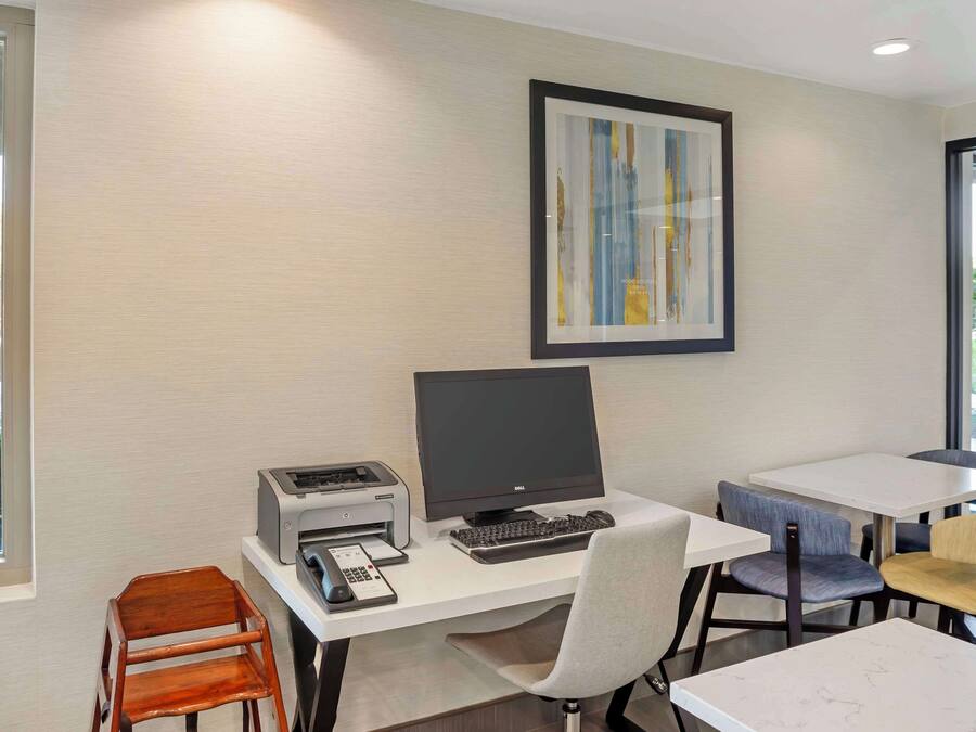 A modern office space with a desktop computer, printer, and two chairs.