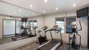 Un gimnasio con cintas de correr, bicicletas estáticas y elípticas.