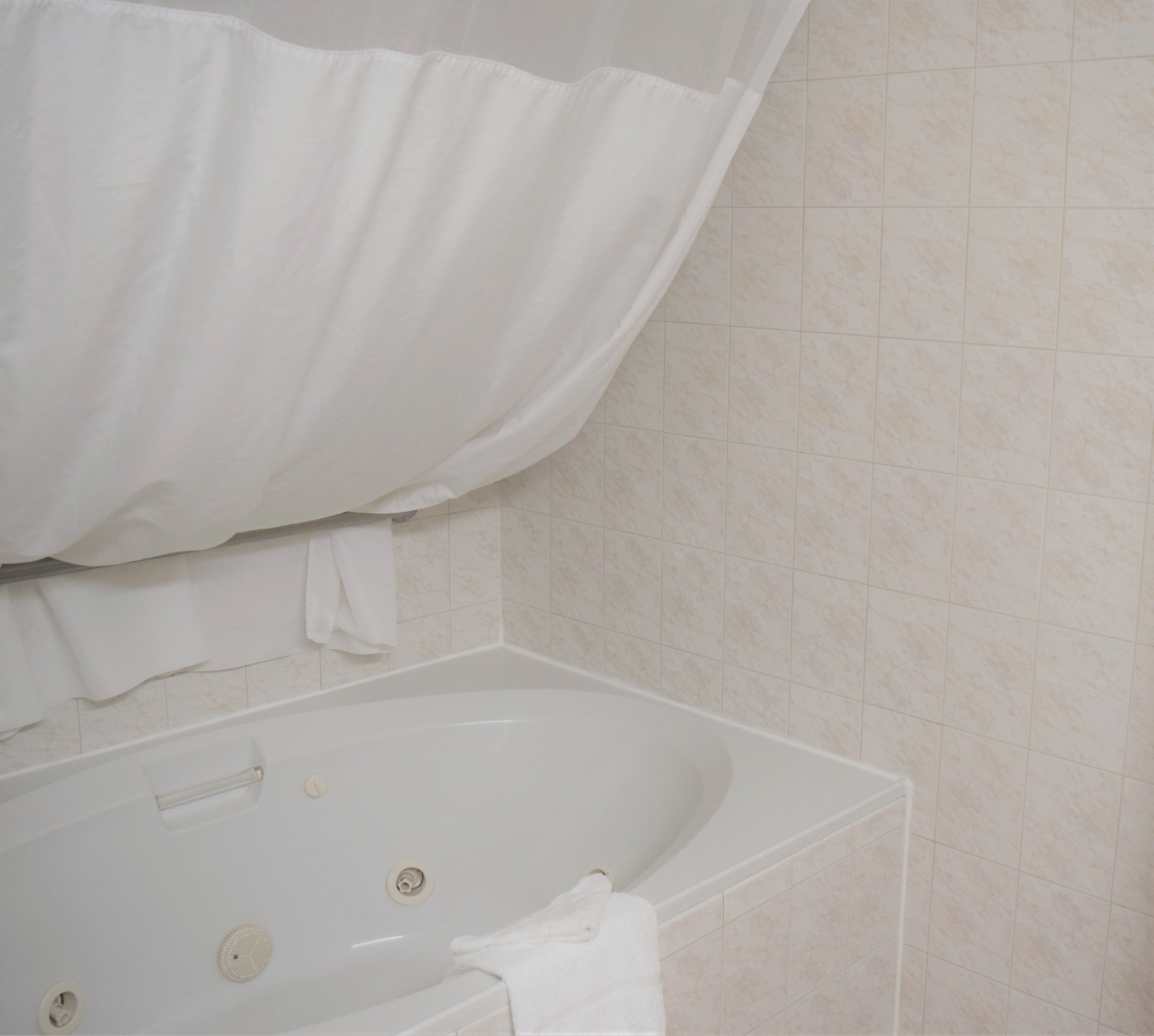 A bathroom with a bathtub, a shower curtain, and tiled walls.