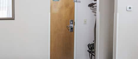 Habitación de hotel con puerta de madera, perchero y termostato en la pared.