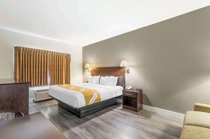 Una habitación de hotel con cama, mesita de noche, lámpara y escritorio.