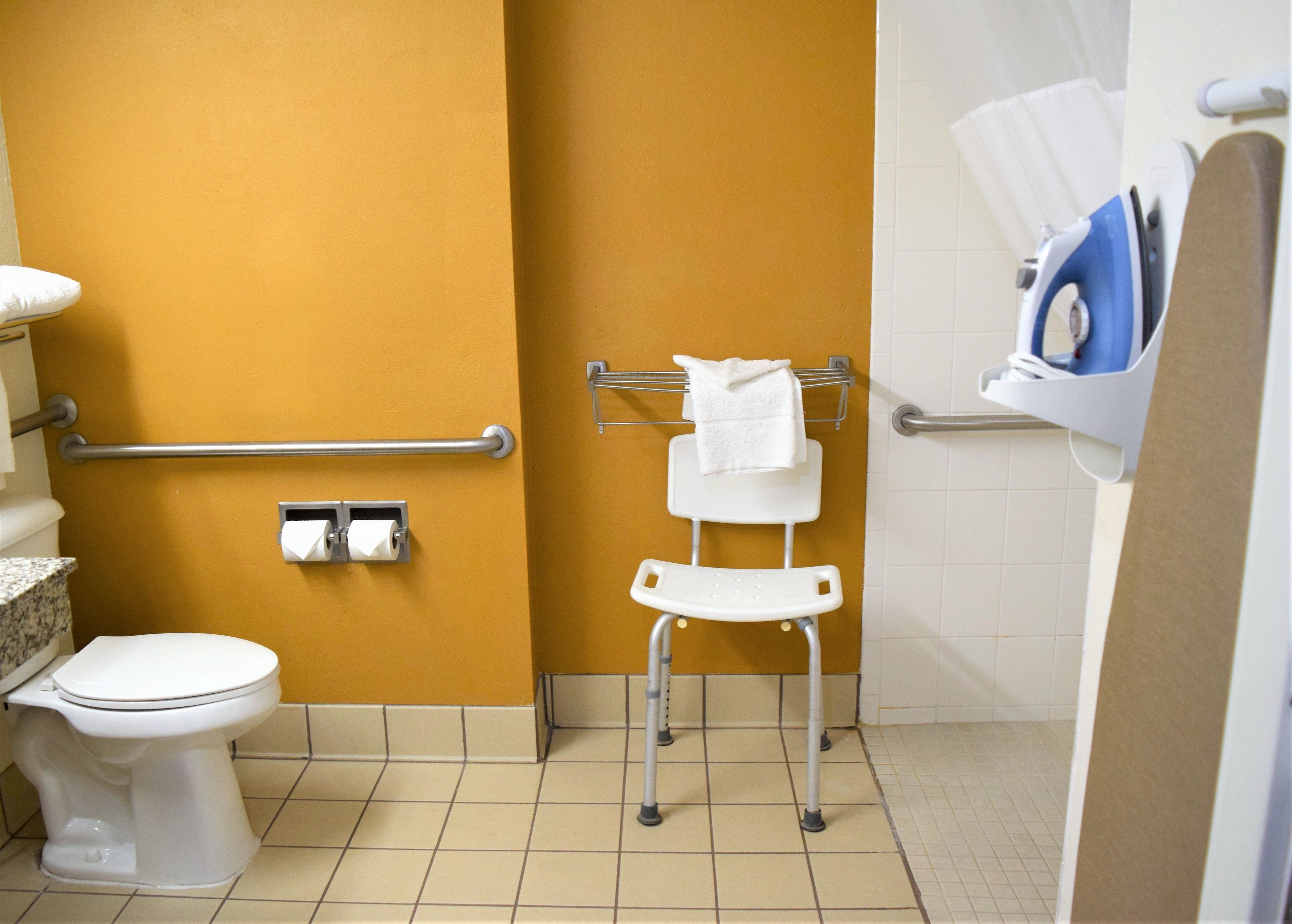Een badkamer met toilet, handdroger, handdoekrek en een douchegedeelte.