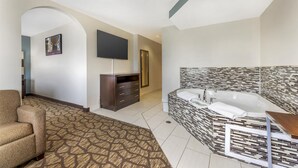 A modern hotel room with a large bathtub, a flat-screen TV, a sofa, and a patterned carpet. - Best Western Joliet Inn & Suites (Joliet)