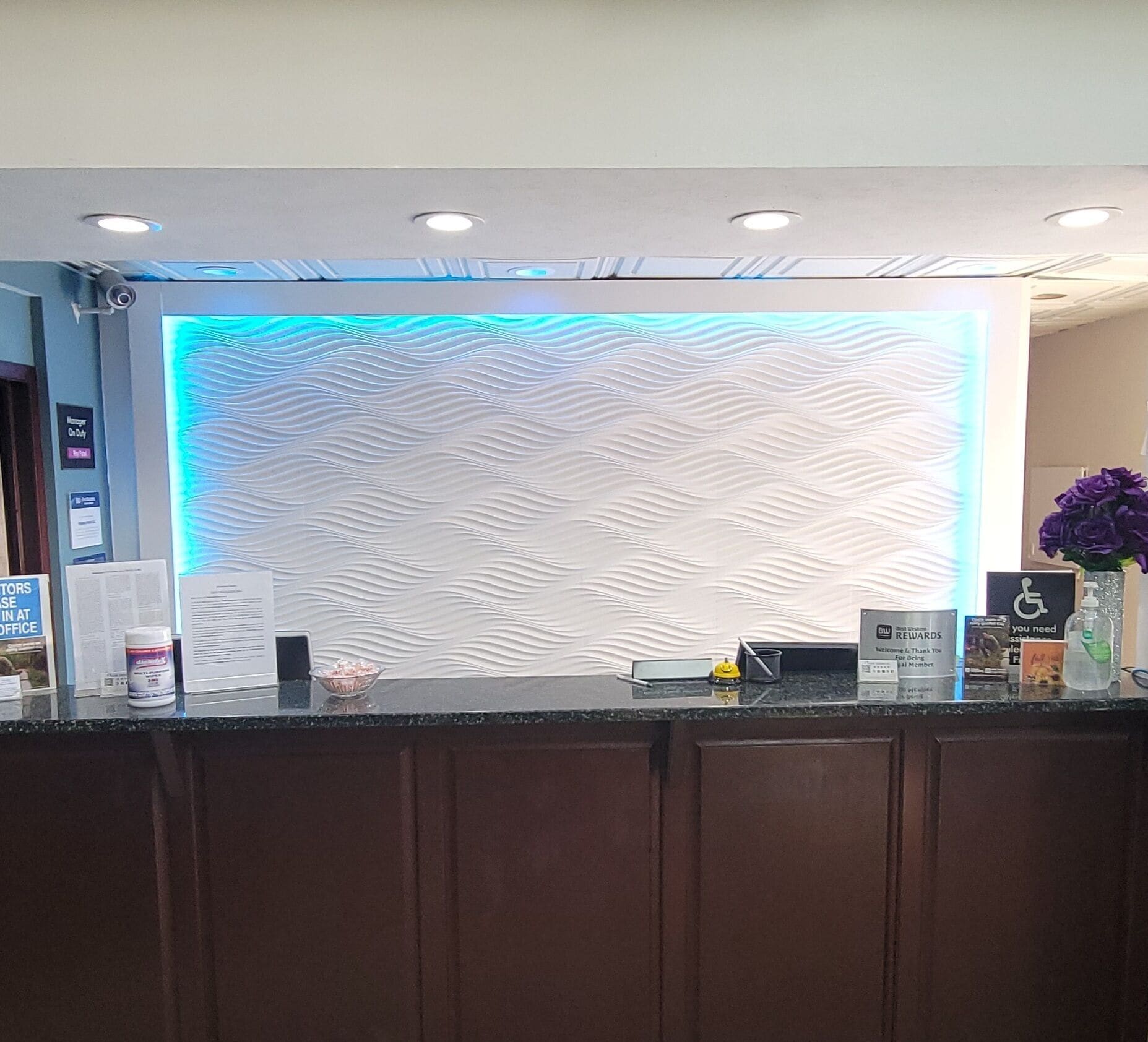 Una mesa de recepción con una pared con textura y una franja de luz azul arriba.