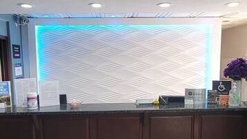 Una mesa de recepción con una pared con textura y una franja de luz azul arriba.
