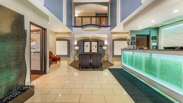 A hotel lobby with a reception desk, seating area, and a glass wall. - Best Western Joliet Inn & Suites (Joliet)