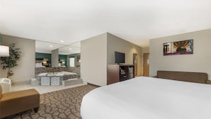 A hotel room with a large bed, a seating area with a sofa and armchairs, a small TV, and a decorative wall piece. - Best Western Joliet Inn & Suites (Joliet)