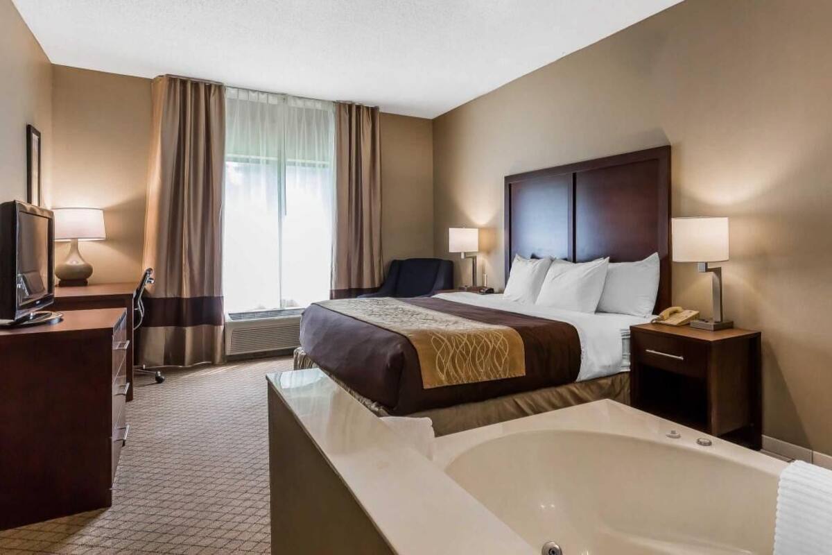 Hotelkamer met een groot bed, een bureau, een stoel, een bureaulamp, een telefoon en een bad.