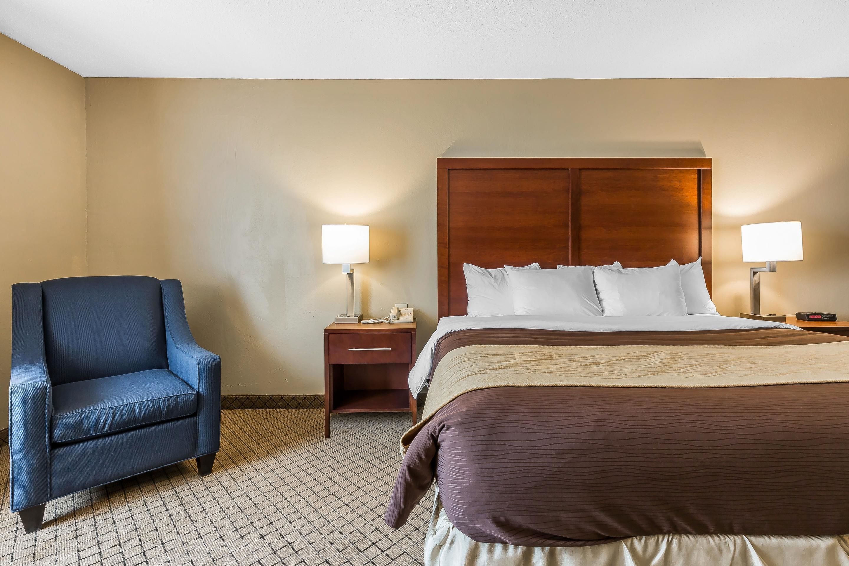 A hotel room with a bed, a chair, and two bedside tables with lamps.
