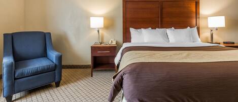 A hotel room with a bed, a chair, and two bedside tables with lamps.