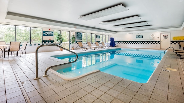 An indoor swimming pool with clear signage, a tiled floor, and a view of the outdoors.
