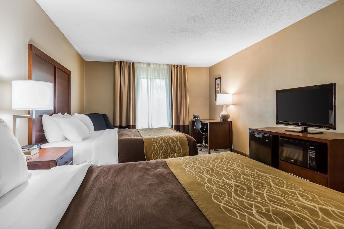 Een hotelkamer met twee bedden, een bureau, een televisie en een minibar.