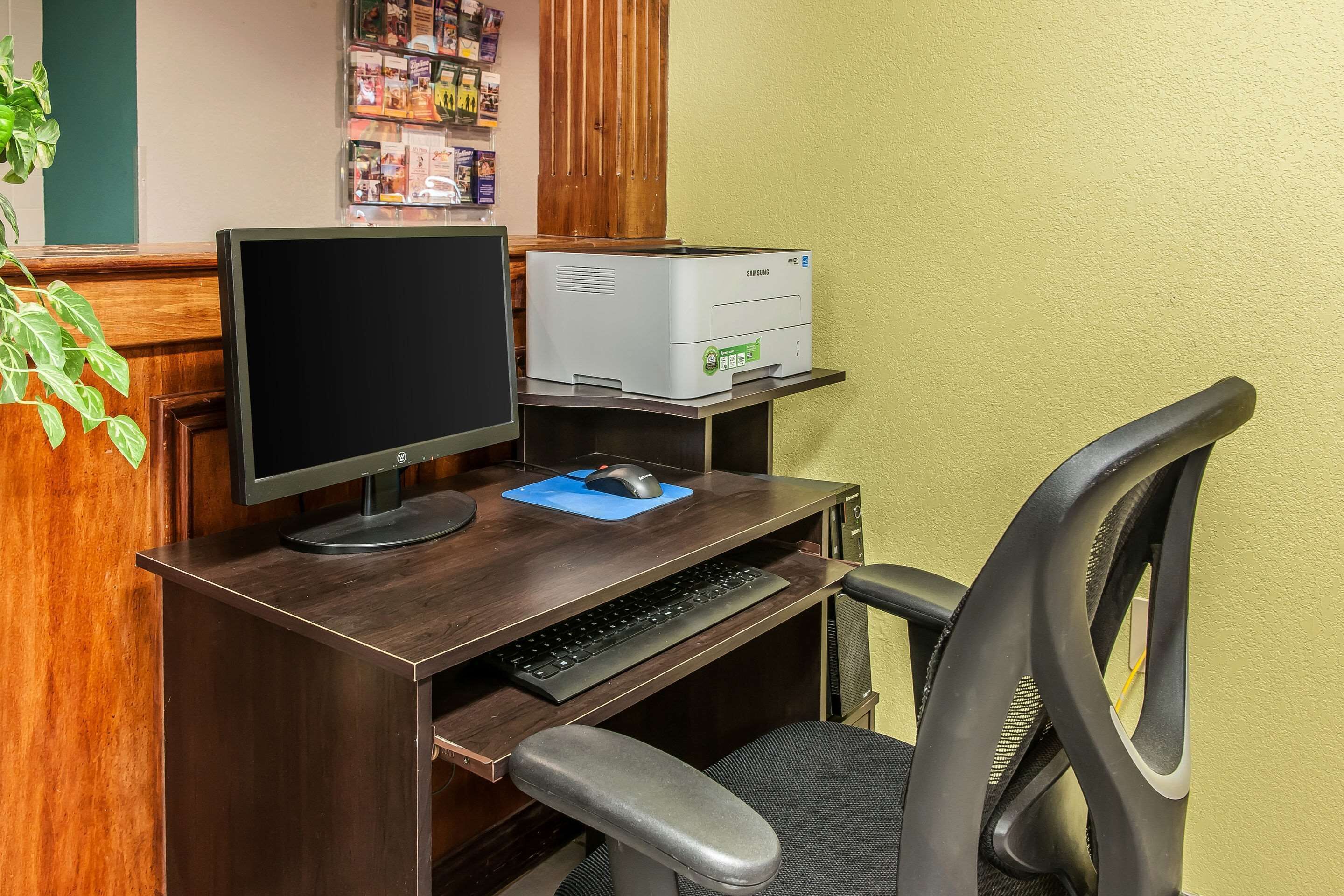 A wooden desk with a computer monitor, keyboard, and printer.