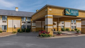 Ett Quality Inn-hotell med en gul fasad, ett parkeringsgarage och en vackert anlagd entré.