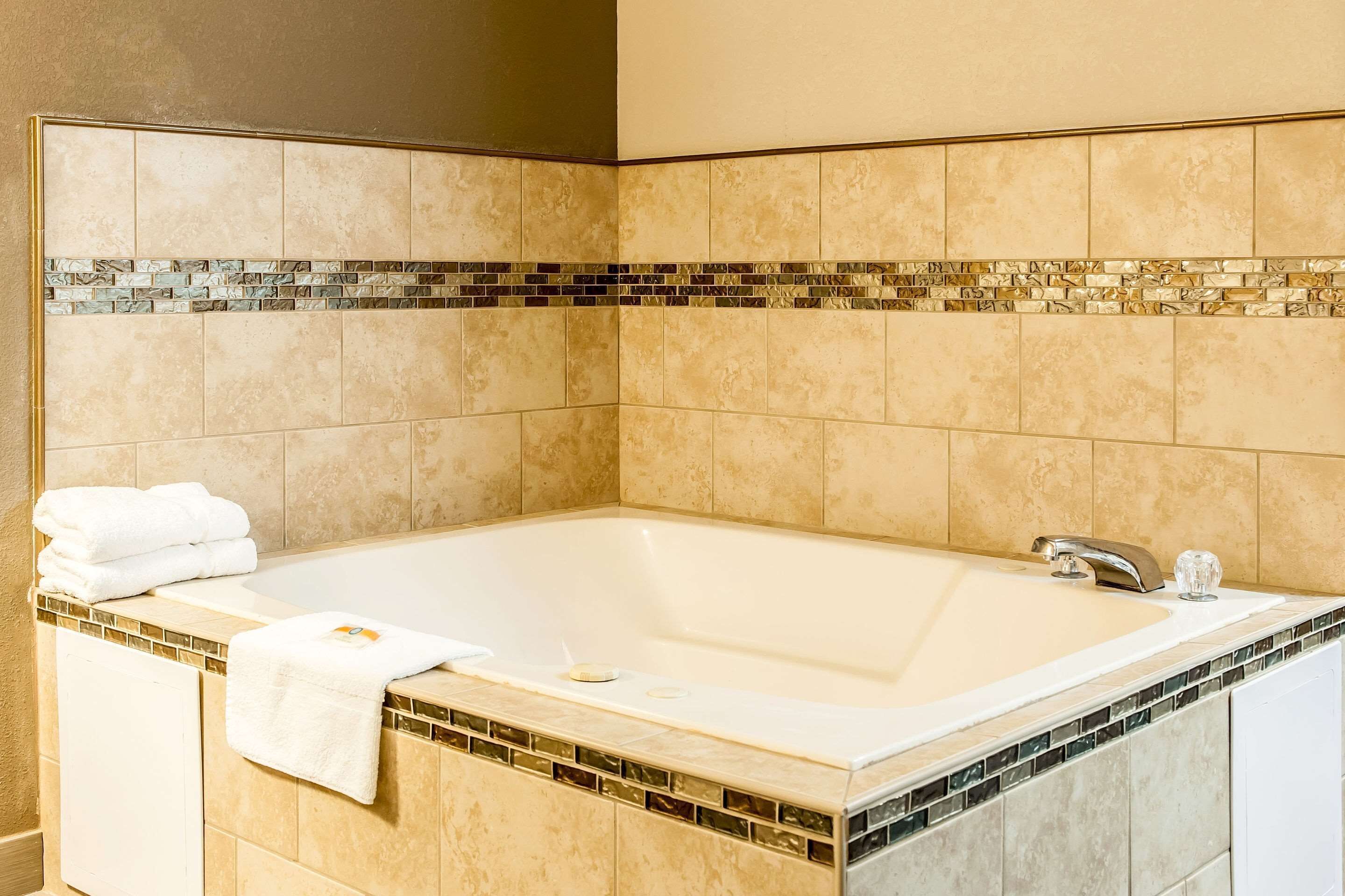 A bathroom with a large bathtub, a sink, and a towel rack.
