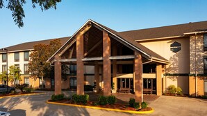 A hotel with a covered entrance, brick pillars, and a parking lot. - Inn at Coushatta (Kinder)