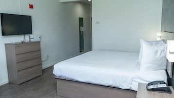 Une chambre d’hôtel avec un lit, une commode, une télévision et un téléphone sur la table de chevet.