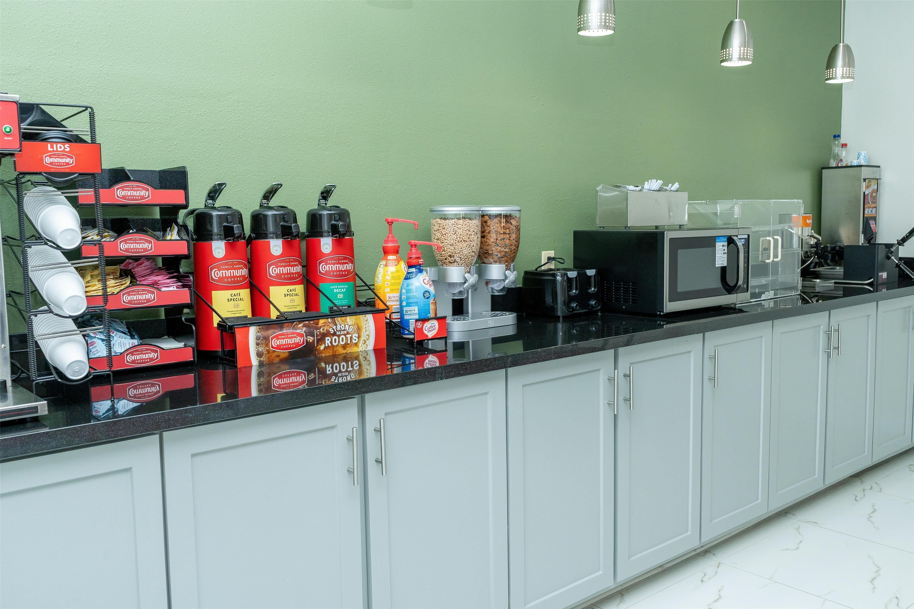 A coffee station with dispensers, a microwave, and a coffee machine.