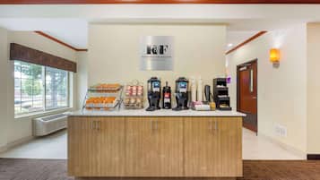 A K&T Coffee Roasters station with coffee makers, a coffee grinder, and a display of coffee beans and pastries.