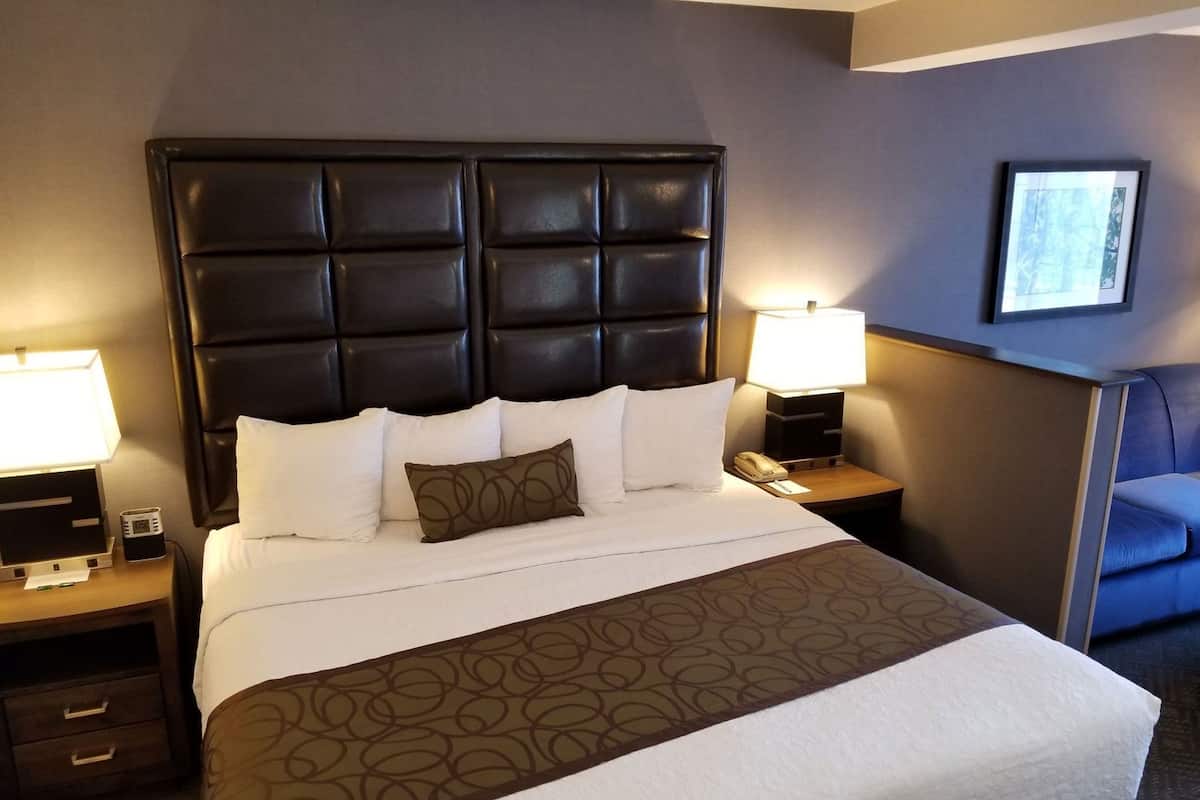 A hotel room with a large bed, two bedside tables with lamps, a small desk, and a chair.