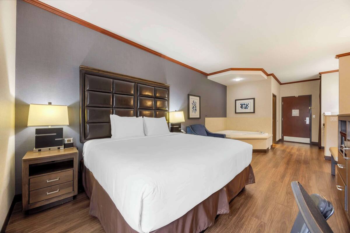 A hotel room with a large bed, bedside tables, a desk, and a chair.