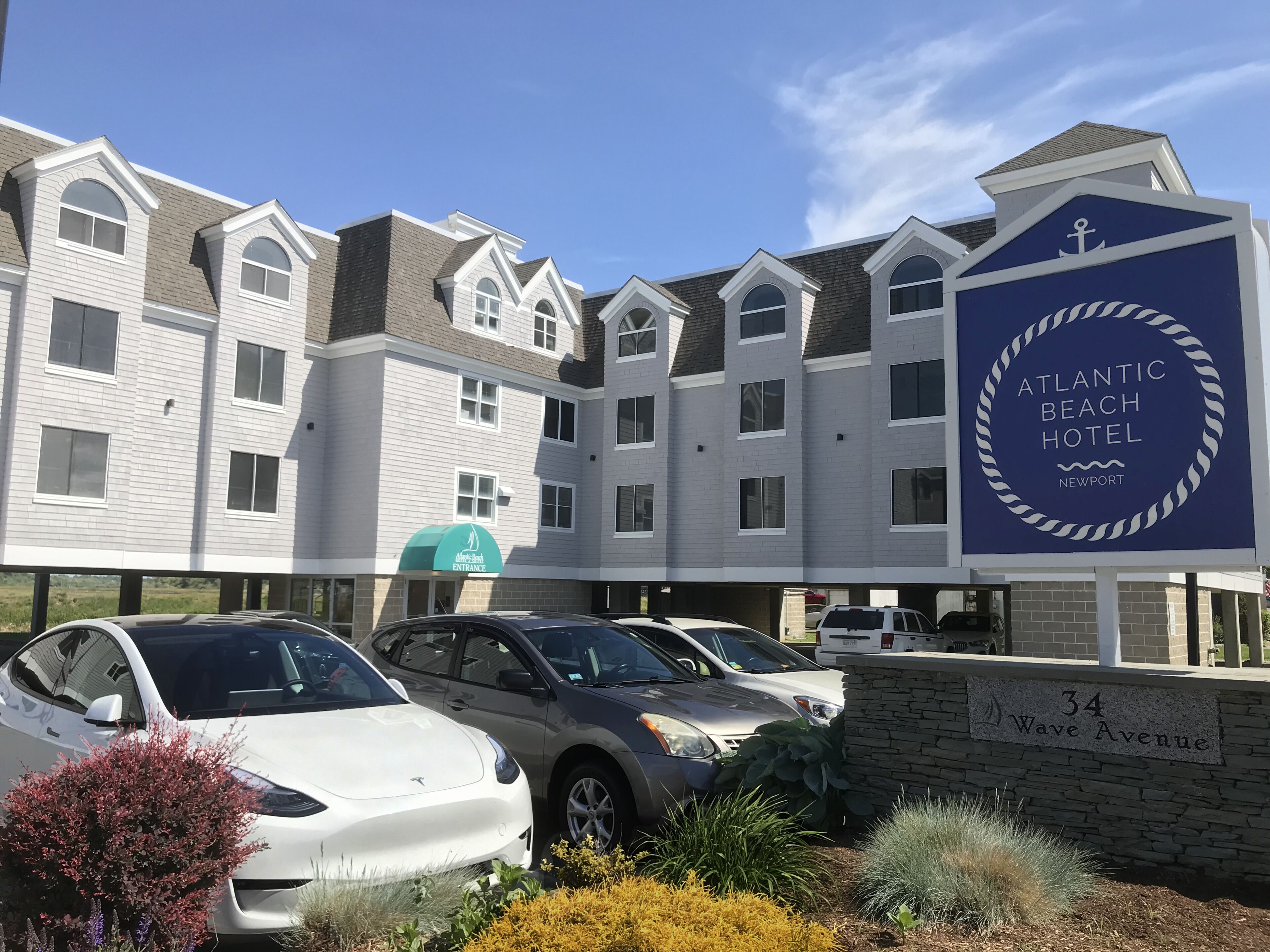Un hotel a più piani con un design architettonico moderno, caratterizzato da un ingresso ben visibile e un logo a tema spiaggia.