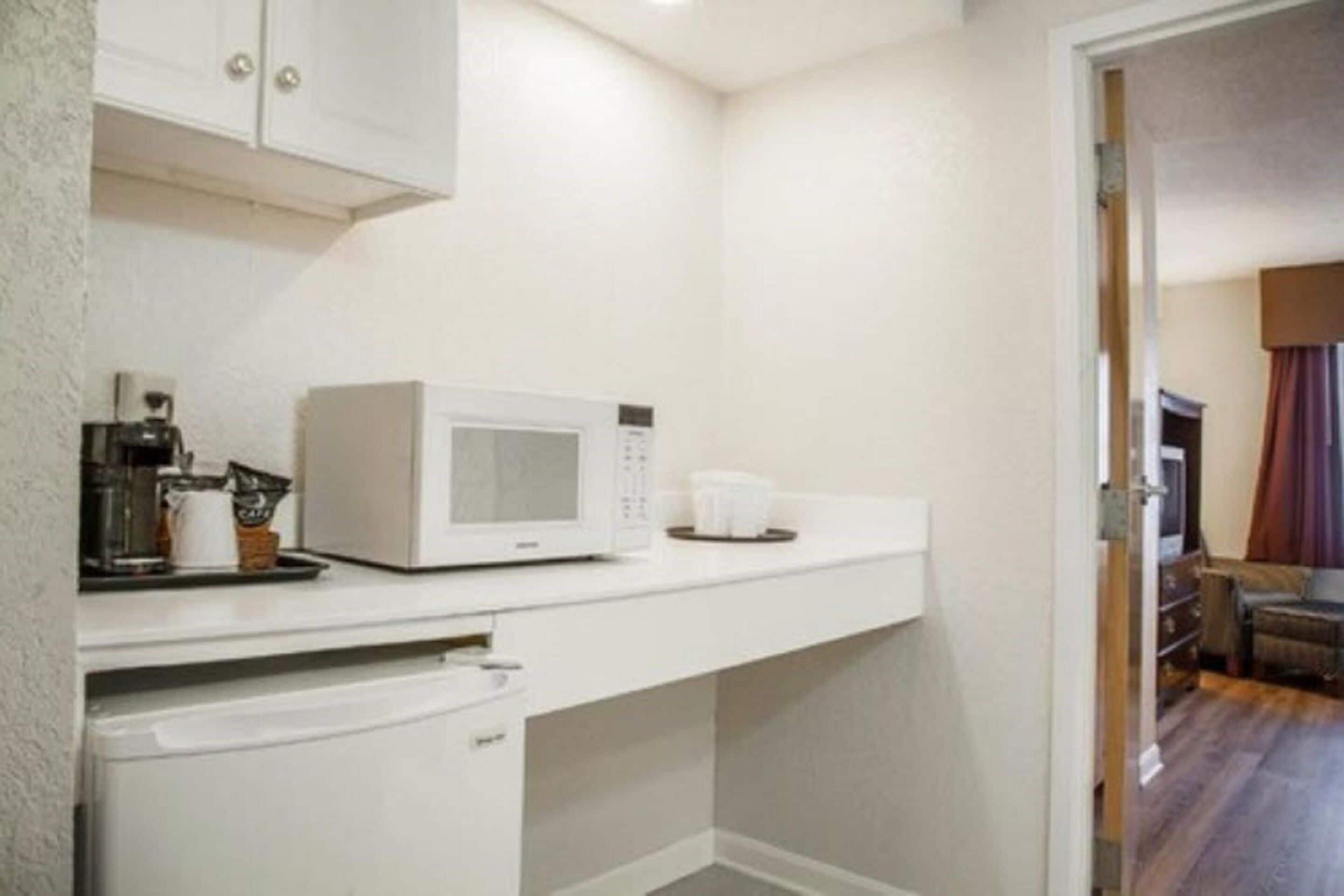A compact kitchenette with a microwave, coffee maker, and a small countertop.