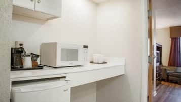 A compact kitchenette with a microwave, coffee maker, and a small countertop.
