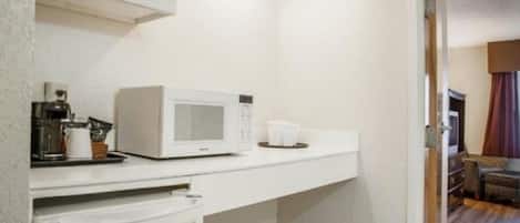 A compact kitchenette with a microwave, coffee maker, and a small countertop.