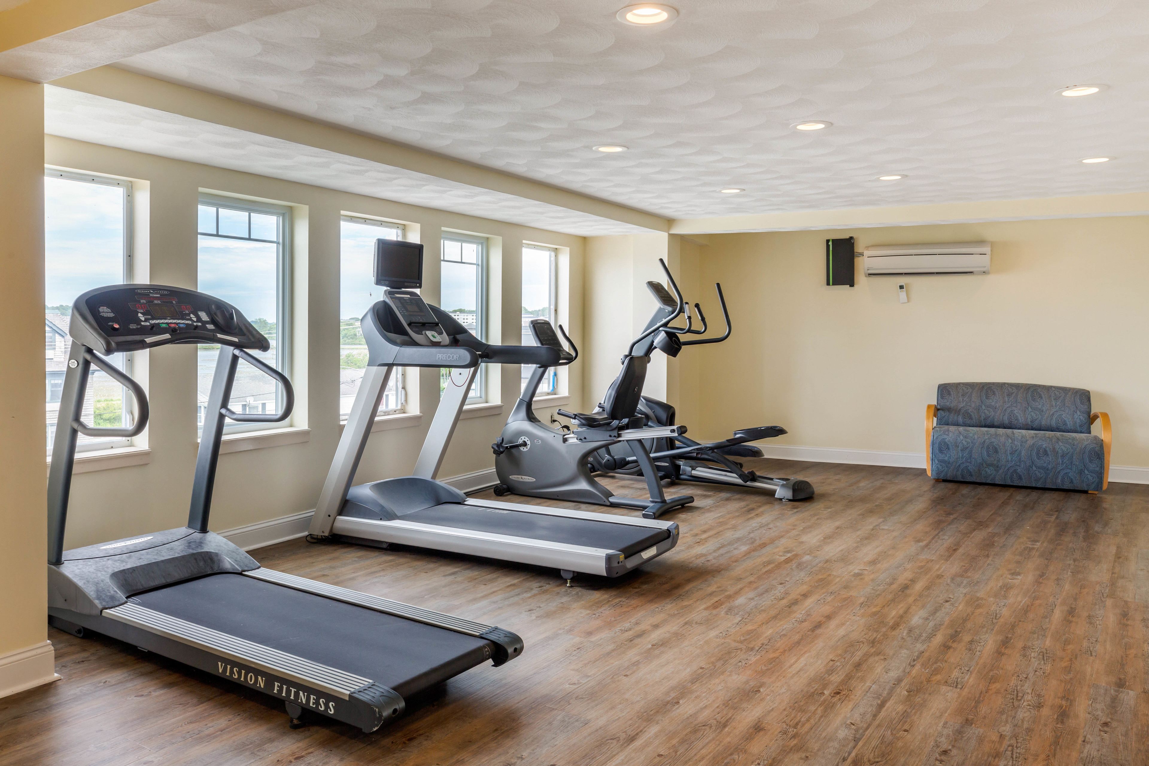 Un gimnasio con cintas de correr, una bicicleta estática y una máquina de remo.