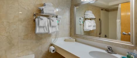 A bathroom with a white sink, a mirror, and a towel rack with folded towels.