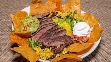 Un plato de nachos con carne, maíz, frijoles y guacamole.