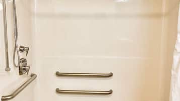 A bathtub with a showerhead, grab bars, and a wooden tray.