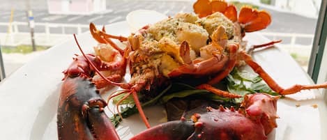 Un plato de langosta con vista al mar y edificios al fondo.