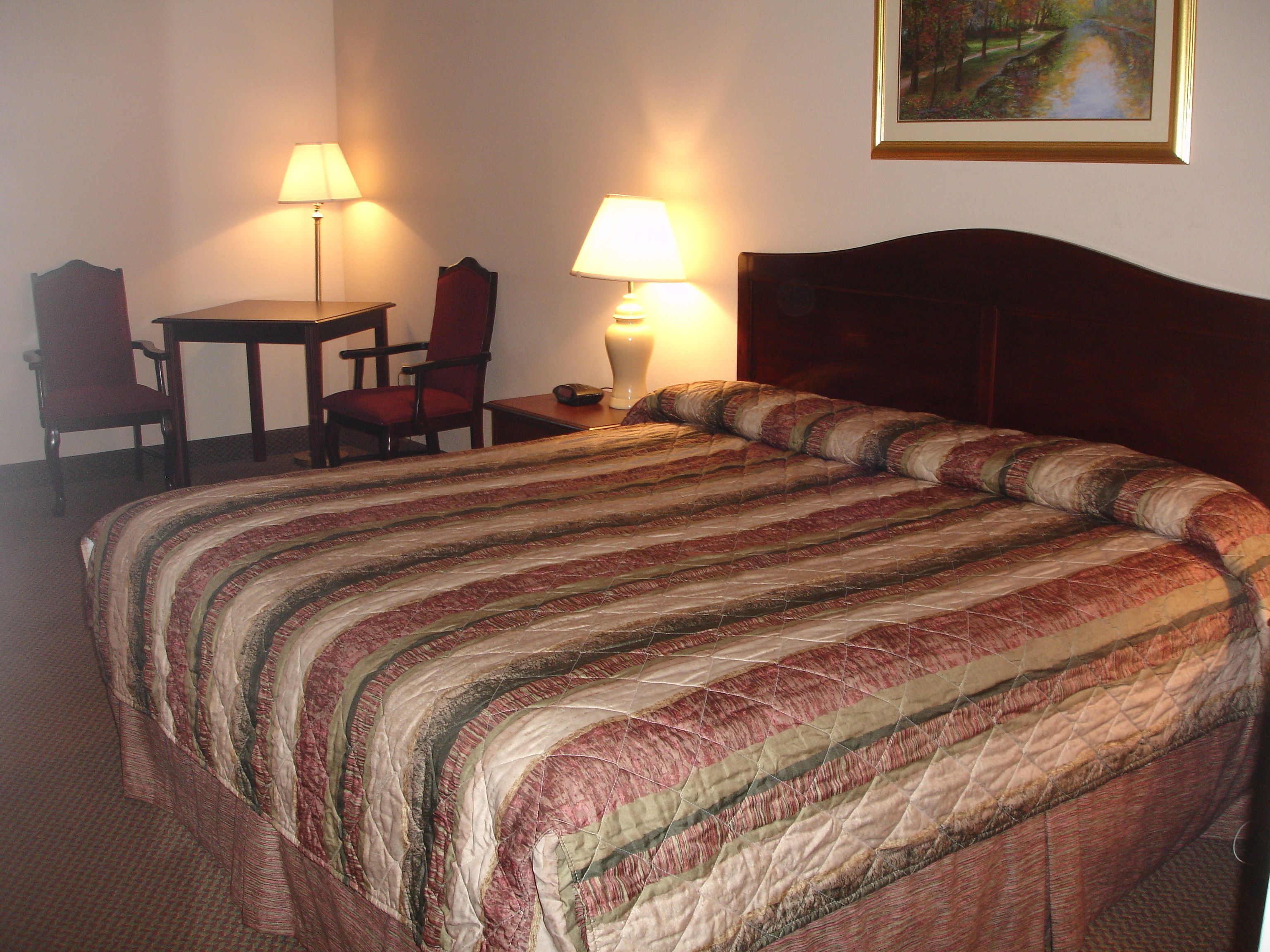 Una habitación de hotel con una cama grande, dos sillones, una mesita y dos lámparas.