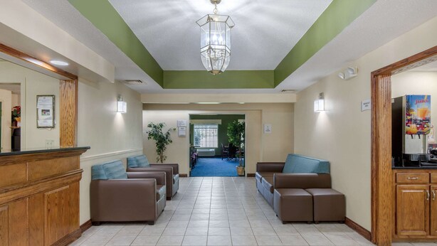 A reception area with a wooden counter, brown leather seating, and a chandelier. - Quality Inn Kingstree North (Kingstree)