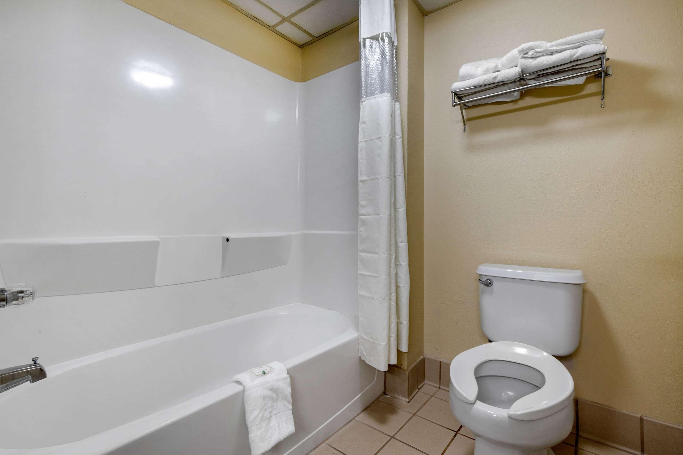 A bathroom with a bathtub, toilet, and a towel rack.
