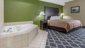 A hotel room with a large bathtub, a bed with a headboard, two bedside tables with lamps, and a patterned rug. - Quality Inn Kingstree North (Kingstree)