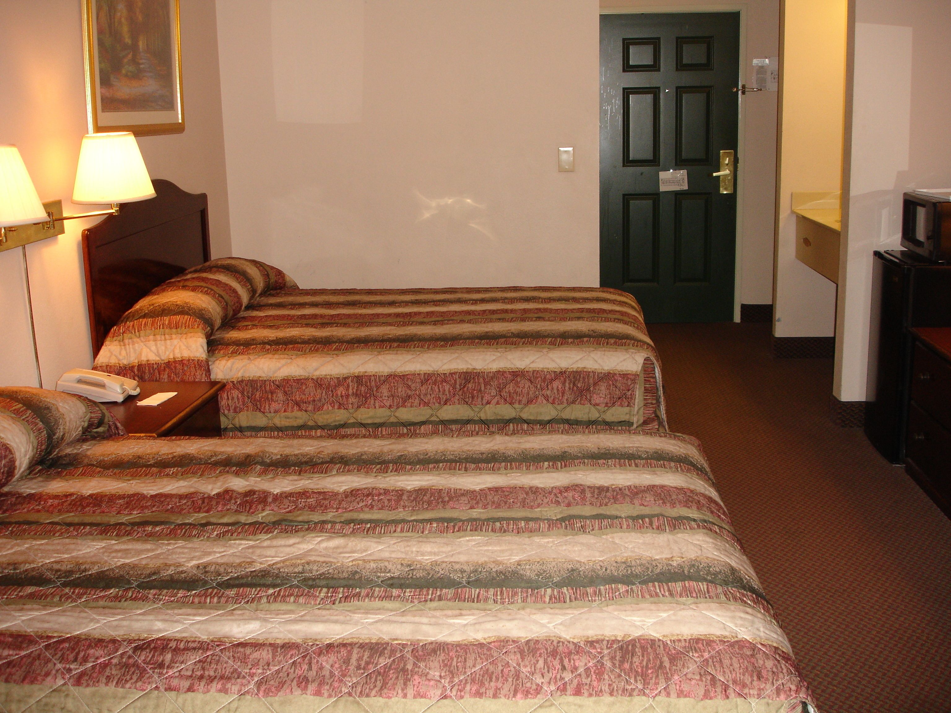 Una habitación de hotel con una cama, un escritorio y una puerta.