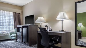 A hotel room with a desk, two lamps, a television, a chair, and a large mirror. - Quality Inn Kingstree North (Kingstree)