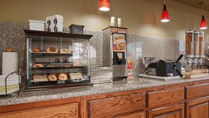 Un comptoir de boulangerie avec une vitrine remplie de produits de boulangerie, une machine à café et un distributeur de café.