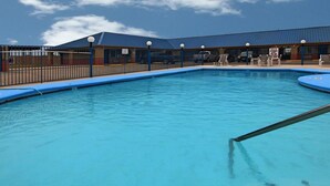 Une piscine dotée d’une plage bleue, entourée d’une clôture et de chaises longues.